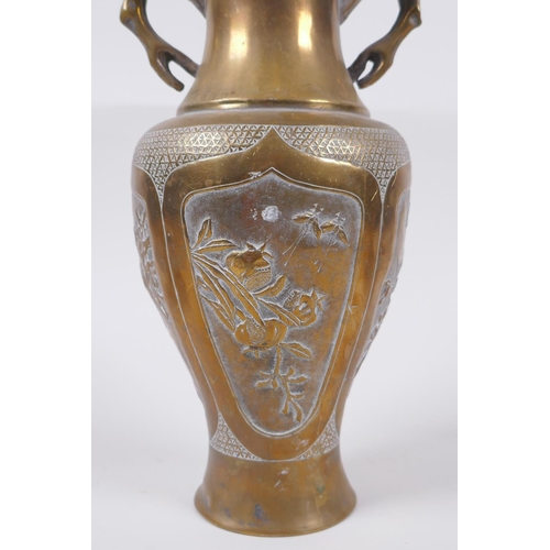 135 - A Japanese Meiji bronze two handled vase with decorative repousse panels depicting birds and insects... 