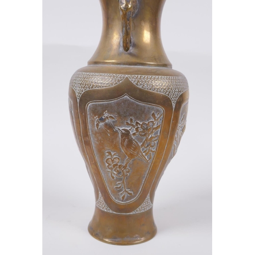 135 - A Japanese Meiji bronze two handled vase with decorative repousse panels depicting birds and insects... 