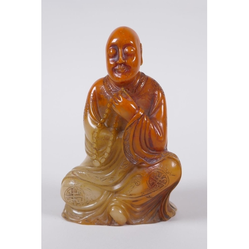 137 - A Chinese faux amber soapstone figure/seal in the form of Lo-han, 12cm high