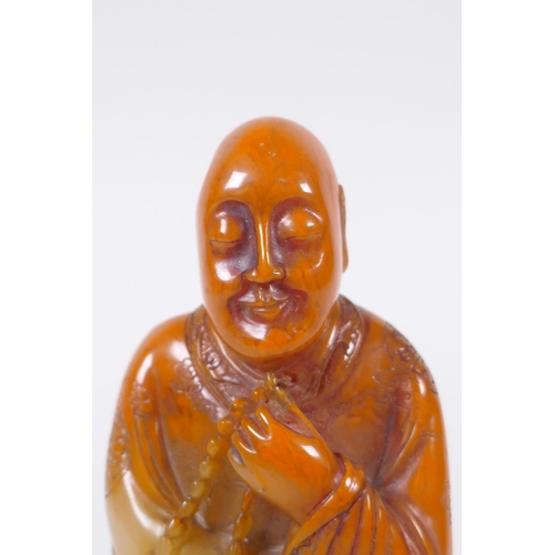 137 - A Chinese faux amber soapstone figure/seal in the form of Lo-han, 12cm high