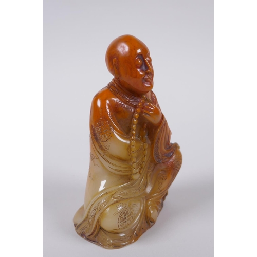 137 - A Chinese faux amber soapstone figure/seal in the form of Lo-han, 12cm high