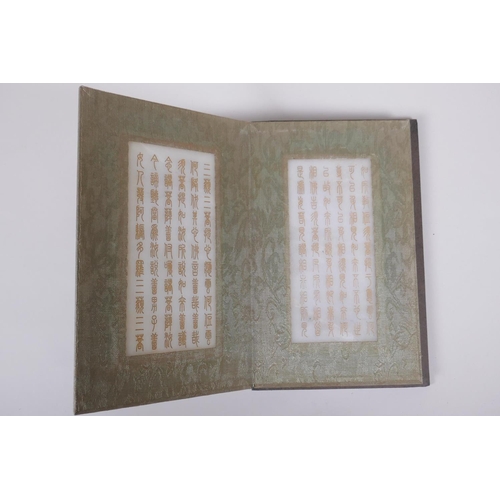 151 - A Chinese wood and silk bound book containing white jade tablets with chased and gilt character insc... 