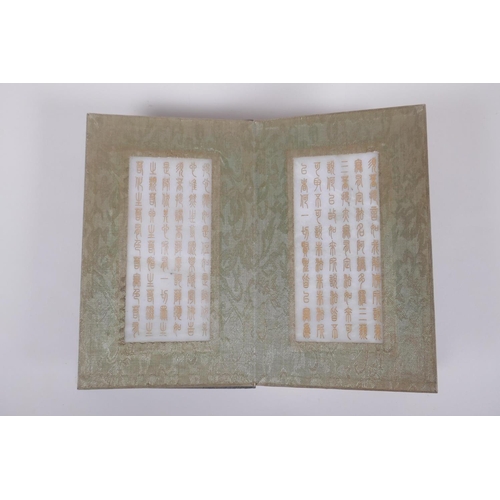 151 - A Chinese wood and silk bound book containing white jade tablets with chased and gilt character insc... 