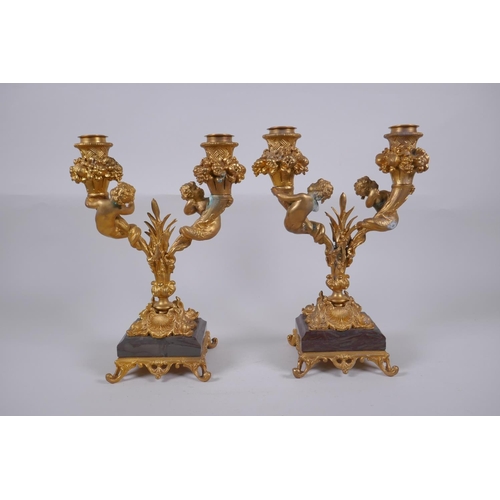 161 - A pair of ormolu two branch candlesticks, decorated with fish tailed putti, 27cm high