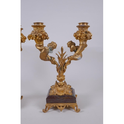 161 - A pair of ormolu two branch candlesticks, decorated with fish tailed putti, 27cm high