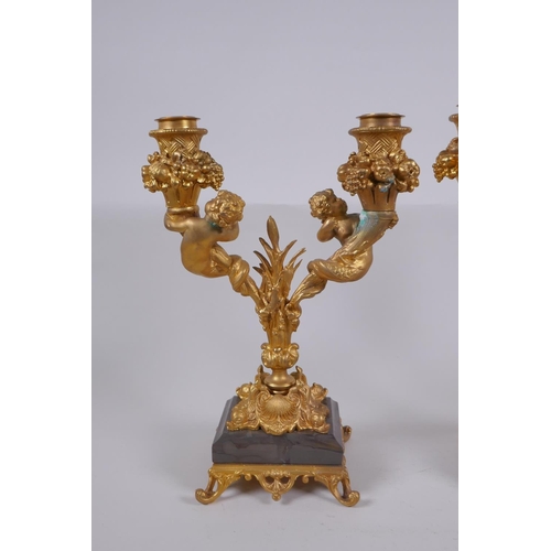 161 - A pair of ormolu two branch candlesticks, decorated with fish tailed putti, 27cm high