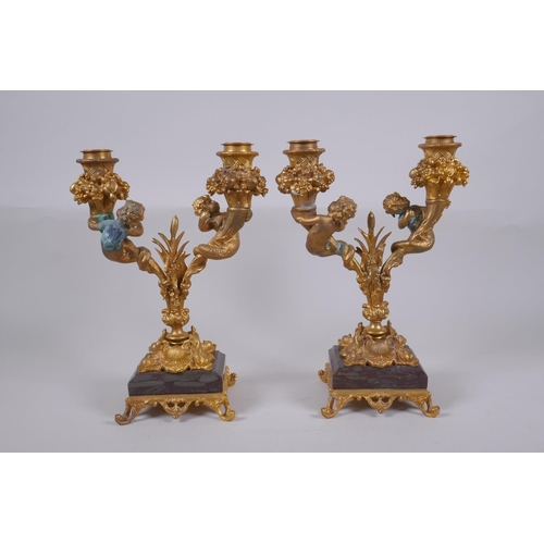 161 - A pair of ormolu two branch candlesticks, decorated with fish tailed putti, 27cm high