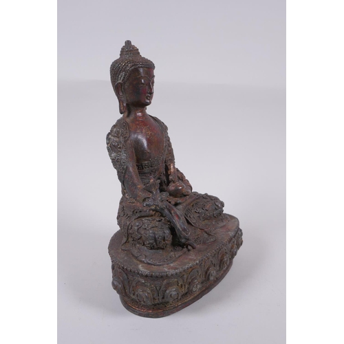 169 - A Tibetan bronzed metal Buddha with the remnants of gilt and copper patina, impressed double vajra m... 