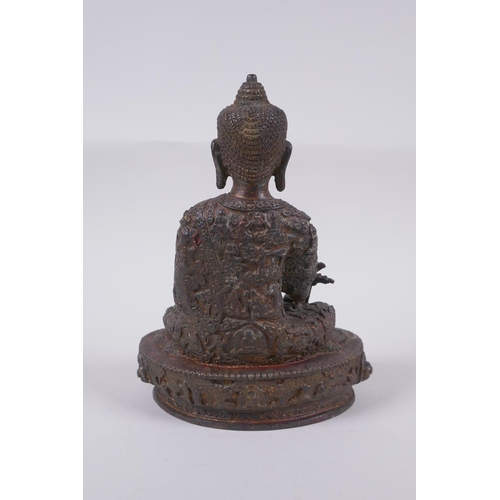 169 - A Tibetan bronzed metal Buddha with the remnants of gilt and copper patina, impressed double vajra m... 