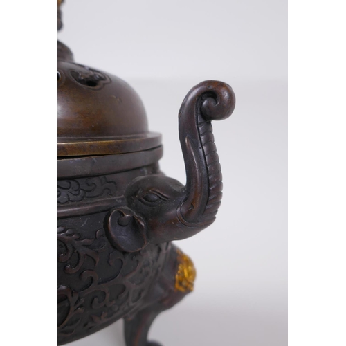 60 - A Chinese bronze two handled censer and cover raised on tripod elephant head feet, with dragon knop,... 