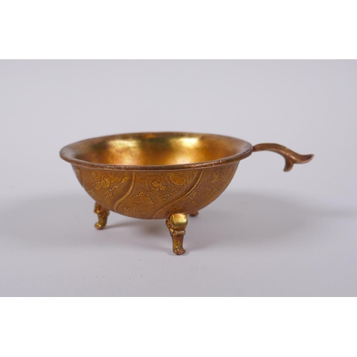 65 - A Chinese gilt metal libation cup on tripod supports with kylin decoration, 9cm diameter