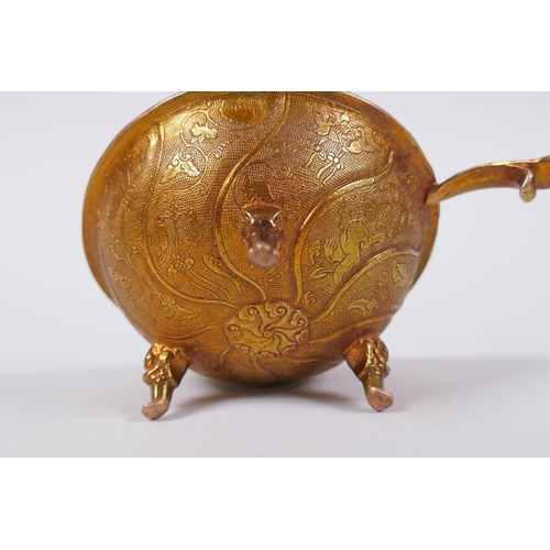 65 - A Chinese gilt metal libation cup on tripod supports with kylin decoration, 9cm diameter