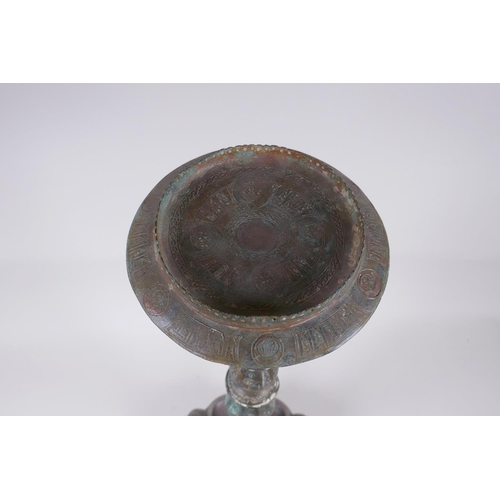 8 - A Persian bronze oil lamp stand, raised on tripod support with engraved script decoration to the col... 