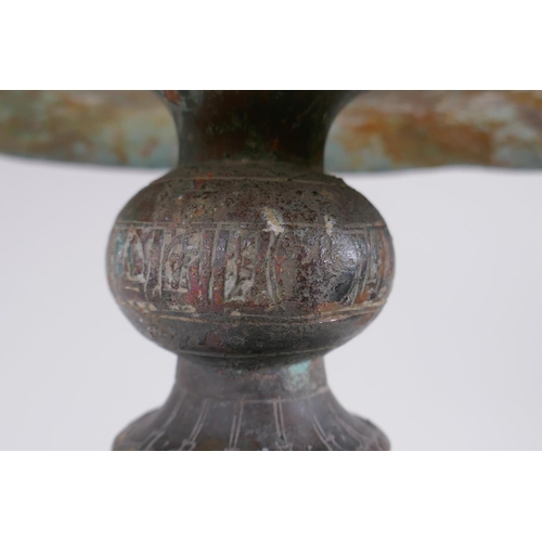 8 - A Persian bronze oil lamp stand, raised on tripod support with engraved script decoration to the col... 