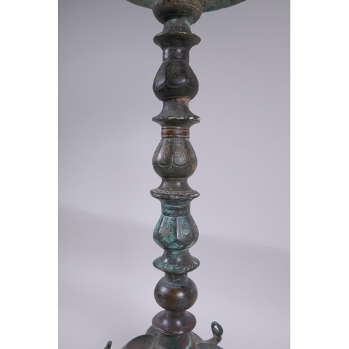 8 - A Persian bronze oil lamp stand, raised on tripod support with engraved script decoration to the col... 