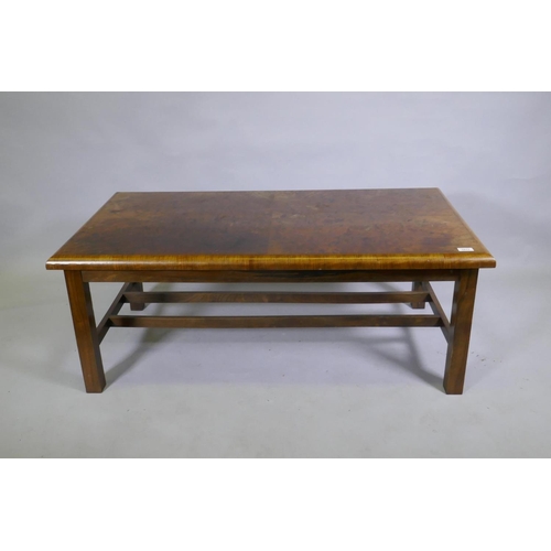 1138 - A burr walnut top coffee table with moulded edge, raised on square supports united by H stretchers, ... 