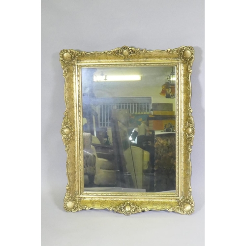 1143 - A gilt composition wall mirror with swept frame, 63 x 79cm