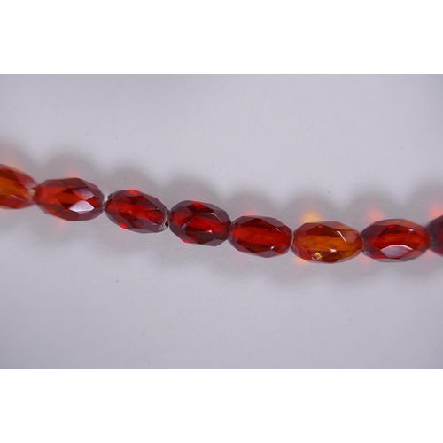 639 - A graduated and faceted honey amber bead necklace, 51cm long, clasp AF