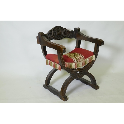 1055 - A C19th oak Glastonbury type throne chair carved with an heraldic coat of arms