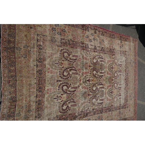 1072 - An antique Persian carpet with stylised flora and fauna designs on a faded gold field, with red bord... 