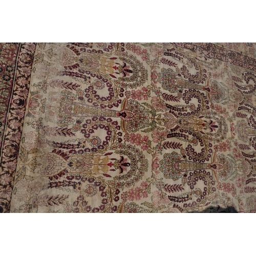 1072 - An antique Persian carpet with stylised flora and fauna designs on a faded gold field, with red bord... 