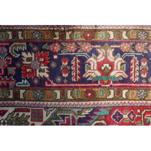 1075 - An antique Persian wool rug with medallion design on a red field with blue borders, 210 x 312cm