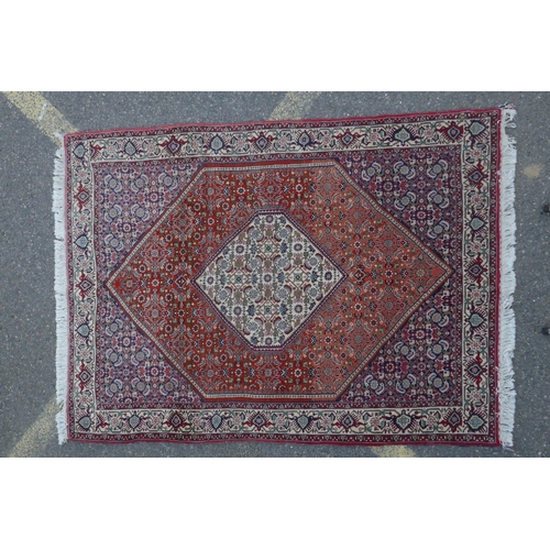 1082 - A red ground Persian Tabriz rug with multicolour allover design and cream borders, 118 x 162cm