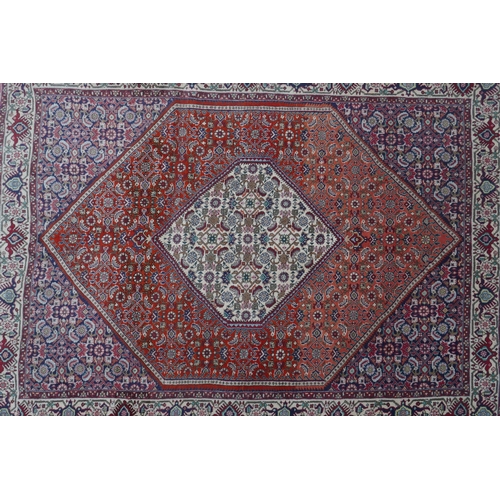 1082 - A red ground Persian Tabriz rug with multicolour allover design and cream borders, 118 x 162cm