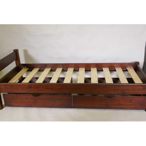 1117 - A stained pine single bed frame with two bespoke under drawers on castors, 64 x 86 x 205cm