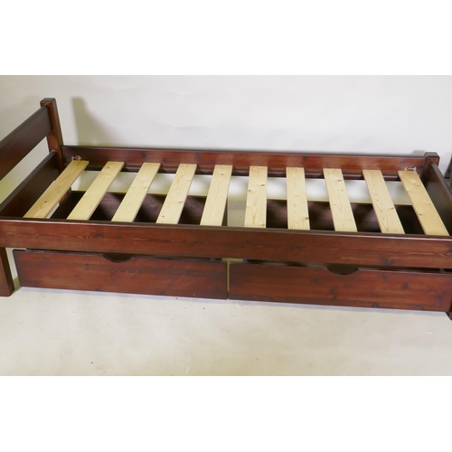 1117 - A stained pine single bed frame with two bespoke under drawers on castors, 64 x 86 x 205cm