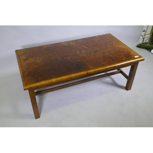 1138 - A burr walnut top coffee table with moulded edge, raised on square supports united by H stretchers, ... 