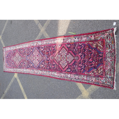 1161 - A Persian red ground wool runner with multi colour geometric medallion design, 85 x 340cm