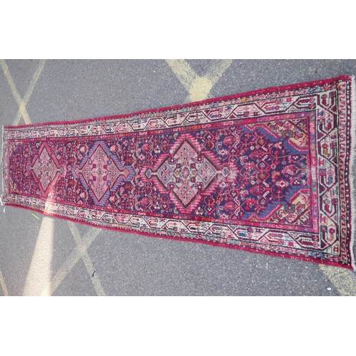 1161 - A Persian red ground wool runner with multi colour geometric medallion design, 85 x 340cm