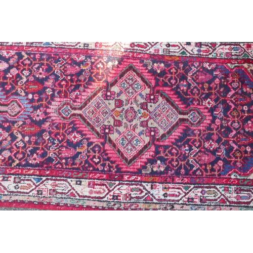 1161 - A Persian red ground wool runner with multi colour geometric medallion design, 85 x 340cm