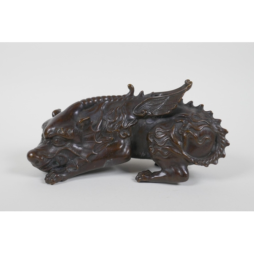 130 - A Chinese filled bronze figure of a winged mythical creature, 20cm long