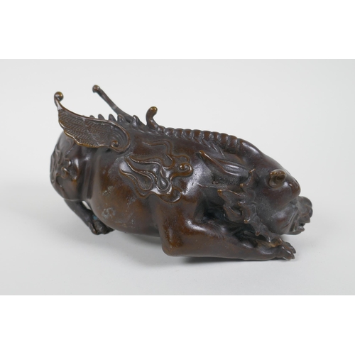 130 - A Chinese filled bronze figure of a winged mythical creature, 20cm long