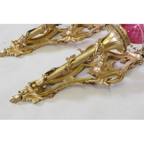 199 - A pair of ormolu wall sconces of trumpet form with leaf swags and cranberry glass shades, 63cm high