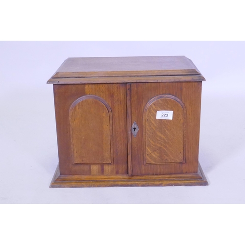 223 - A Victorian golden oak smoker's companion, with two doors opening to reveal a fitted interior with s... 