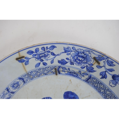 338 - A C19th Delft tin glazed charger decorated with flowers and butterflies, AF, historic repair, 31cm d... 