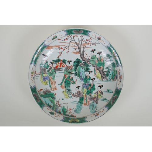 38 - A Chinese KangXi style famille verte porcelain charger decorated with women in a landscape, vase mar... 