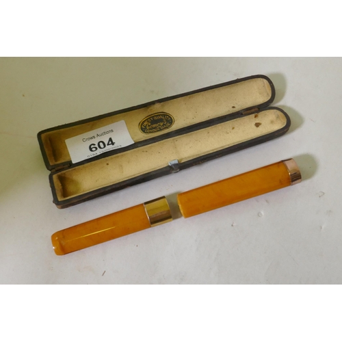 604 - A Victorian amber cigar holder with 9ct gold mounts, cased with label Comoys London, 14cm long, AF