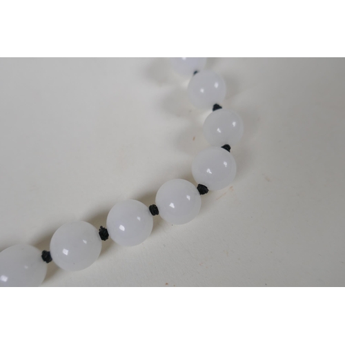 614 - An apple green jade beaded necklace, together with a similar white jade beaded necklace, 70cm long