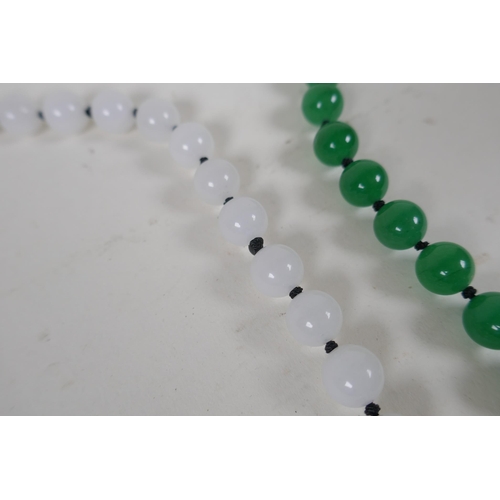 614 - An apple green jade beaded necklace, together with a similar white jade beaded necklace, 70cm long