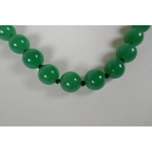 614 - An apple green jade beaded necklace, together with a similar white jade beaded necklace, 70cm long