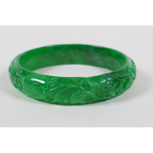 625 - A Chinese carved apple green jade bangle, and a green hardstone archers ring, bangle 7cm diameter