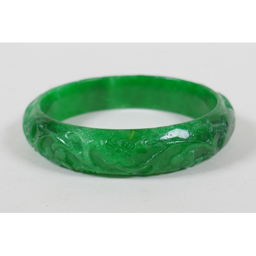 625 - A Chinese carved apple green jade bangle, and a green hardstone archers ring, bangle 7cm diameter