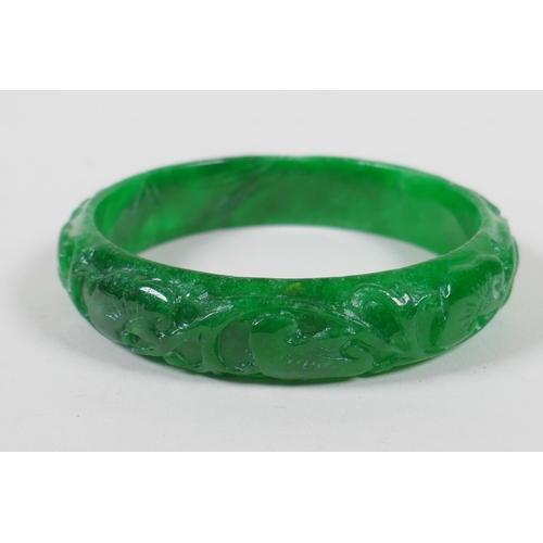 625 - A Chinese carved apple green jade bangle, and a green hardstone archers ring, bangle 7cm diameter