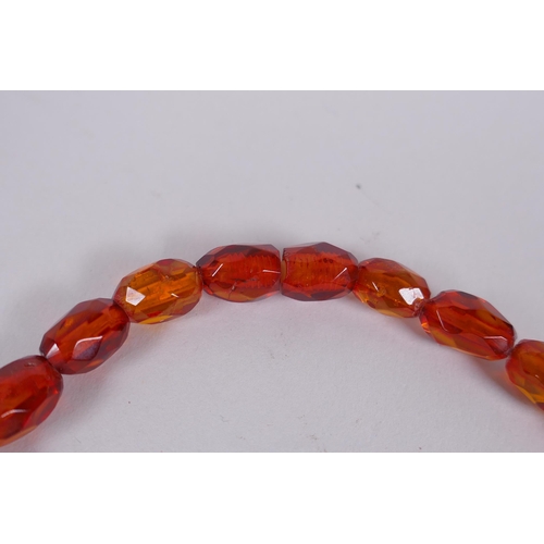 639 - A graduated and faceted honey amber bead necklace, 51cm long, clasp AF