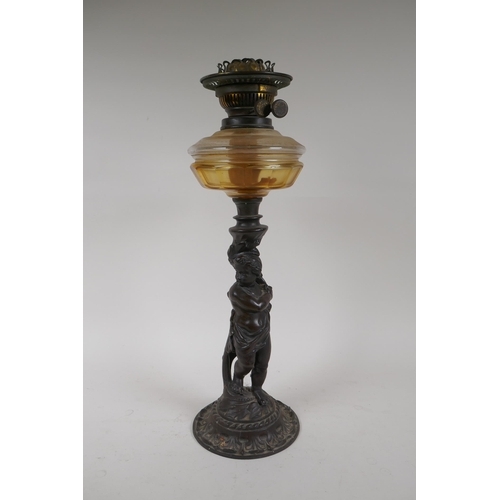 3 - An early C20th oil lamp with cast iron base in the form of a putto, 47cm high