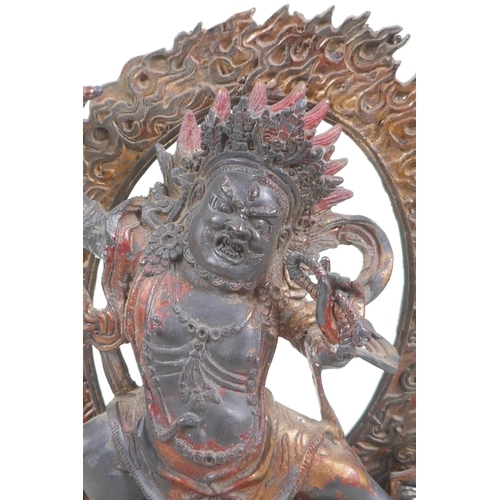 37 - A Tibetan bronze figure of a wrathful deity, with the remnants of gilt patina, 24cm high